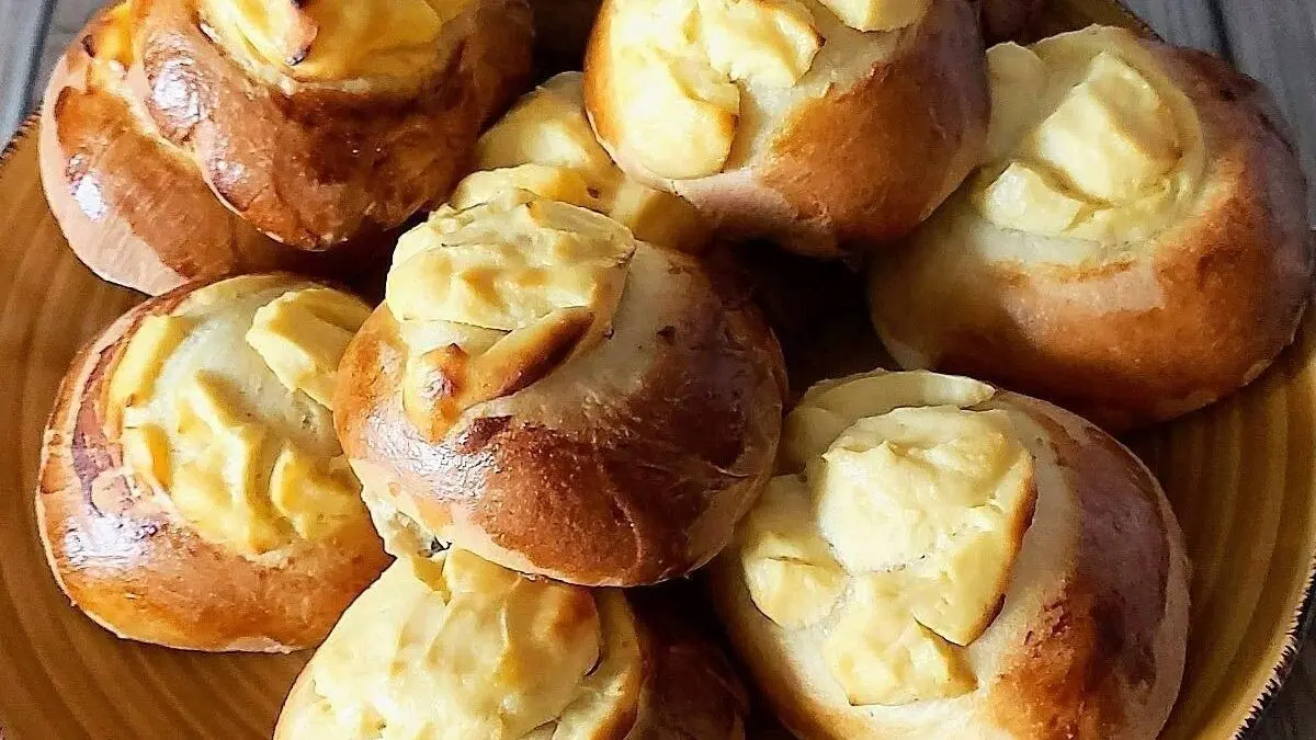 Runde Quarkgeb&auml;ckst&uuml;cke liegen auf einem braunen Teller, frisch gebacken und goldbraun mit einer cremigen F&uuml;llung.