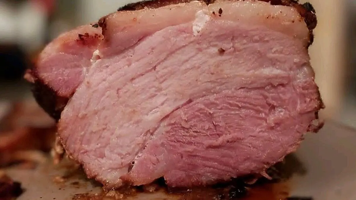 Saftiger Krustenbraten liegt auf einem Teller, gleichm&auml;&szlig;ig geschnitten, mit knuspriger Kruste und zartem Fleisch.