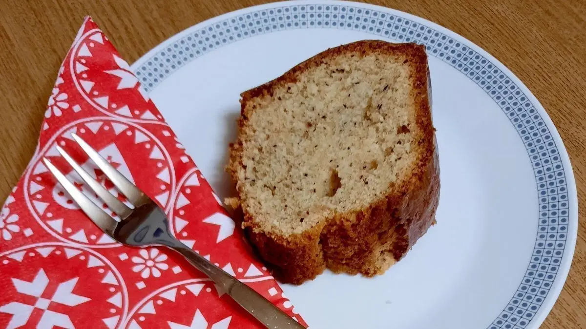 Ein St&uuml;ck Nusskuchen liegt auf einem wei&szlig;en Teller, umgeben von einer roten Serviette, bereit zum Genie&szlig;en.