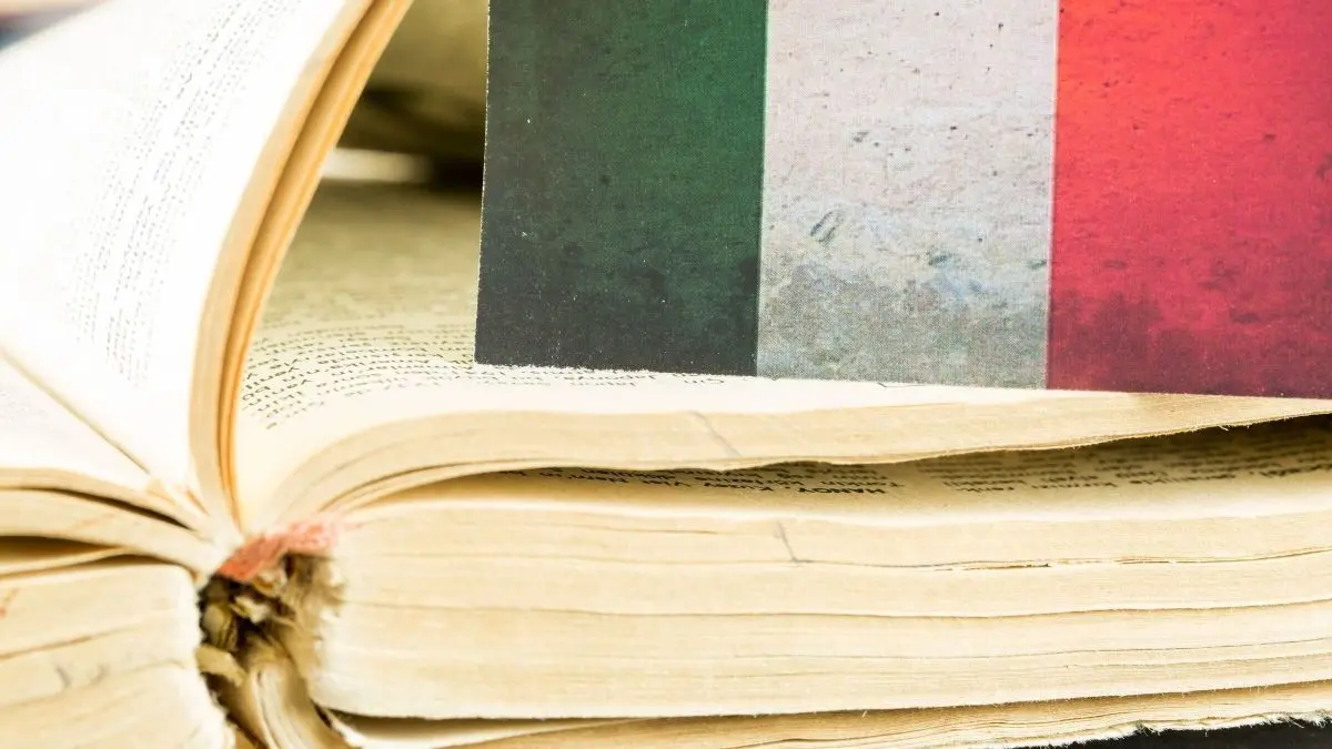 Ein aufgeschlagenes Buch liegt offen, w&auml;hrend eine italienische Flagge darauf sichtbar ist. Typische italienische Begriffe werden vermittelt.