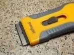 Sekundenkleber auf dem Tisch mit Glaskeramikfeldkratzer entfernen