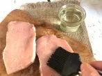 Unpanierte Schnitzel mit dem Pinsel mit Öl bestreichen