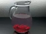 Aromatisiertes Wasser: Zerdrückte Himbeeren in einen Krug mit Wasser