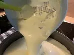 Nachdem die Schokost&uuml;cke zum Teig gegeben und verr&uuml;hrt wurden, die K&auml;semasse dann auf den Keksboden gie&szlig;en.