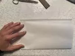 Einen Bogen Butterbrotpapier hochkant hinlegen und die untere H&auml;lfte nach oben falten. Dabei ist es wichtig, dass die hintere H&auml;lfte 1 cm herausschaut. 