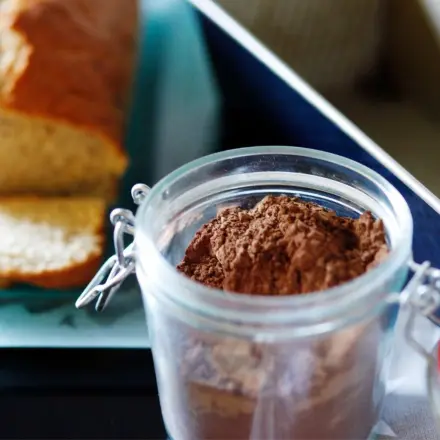 Kuchenform mit Kakaopulver ausstreuen