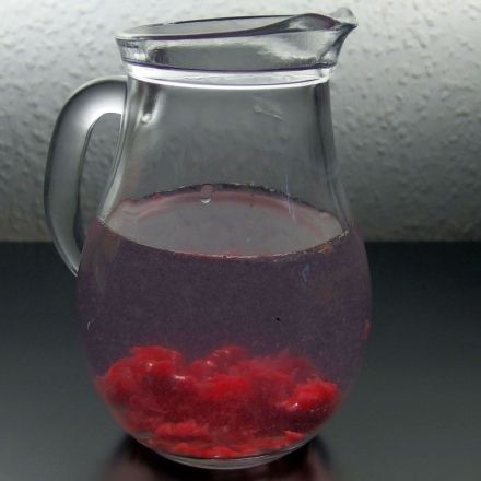 Aromatisiertes Wasser: Zerdrückte Himbeeren in einen Krug mit Wasser