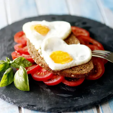 Gesunder Frühstücksteller mit Spiegeleier in Herzfrom