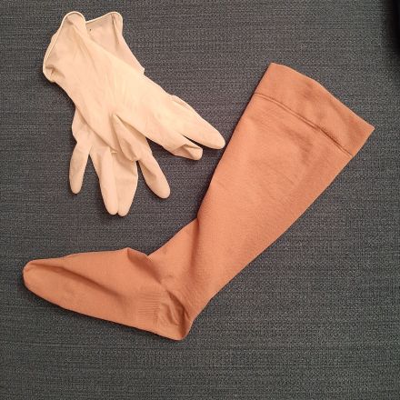 Kompressionsstrumpf mithilfe von Einmalhandschuhen anziehen
