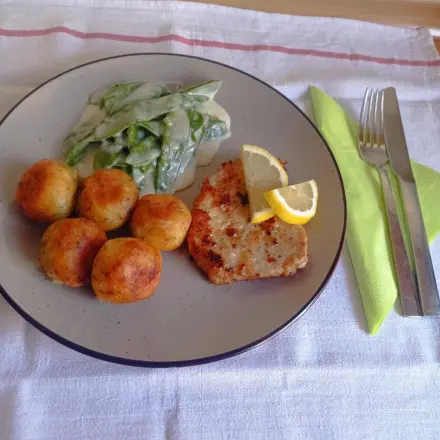 Schweineschnitzel mit Kartoffelbällchen und Zuckerschoten