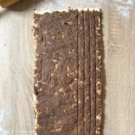 Den Hefeteig ausrollen und mit der saftigen Nussf&uuml;llung bestreichen. Jetzt kannst du ihn auch schon in Streifen teilen.