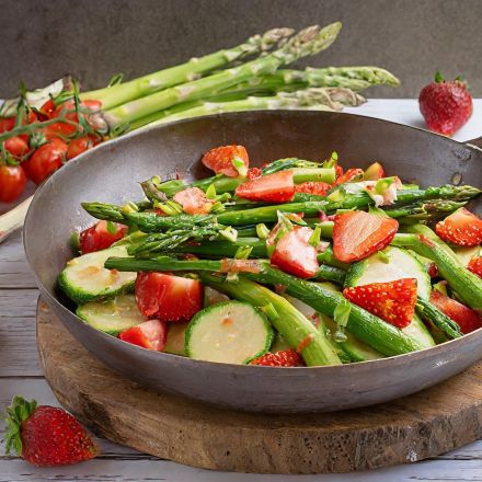 Bunte Gemüsepfanne mit grünem Spargel und Erdbeeren