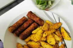 Cevapcici mit Kartoffelspalten und Feldsalat