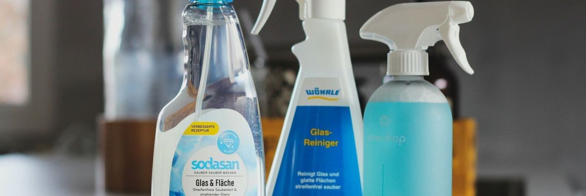 Sodasan und Wöhrle Putzmittel stehen auf einem Tisch, bereit zum Putzen. Im Hintergrund sind weitere Reinigungsutensilien zu sehen.